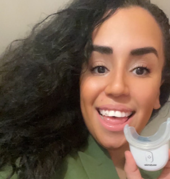 Mohiba Talhaoui smiler og holder opp WeSmiles LED-skinne